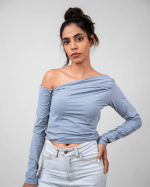 Model wearing a grey asymmetrical top in a standing pose, showcasing the front design.