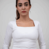 Model wearing a white square top in a standing pose, showcasing the front design.